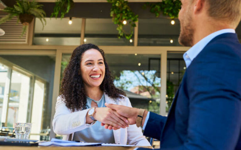 woman and man seated at a table shaking hands