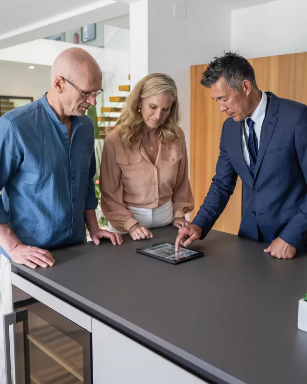 three people viewing tablet in kitchen in new home