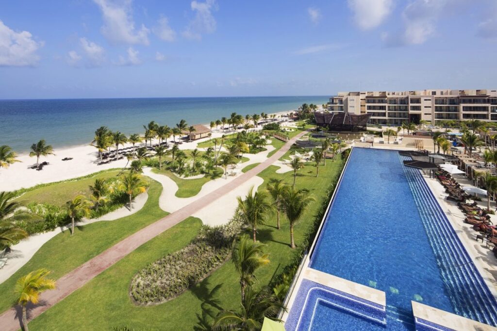 pool, grass, and ocean view of hotel