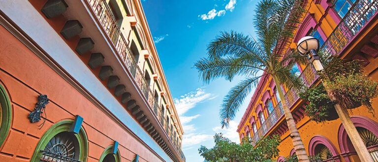 Mazatlan street with colorful orange buildings and palm trees