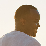 Associate testimonial portrait of a man looking over his shoulder outdoors